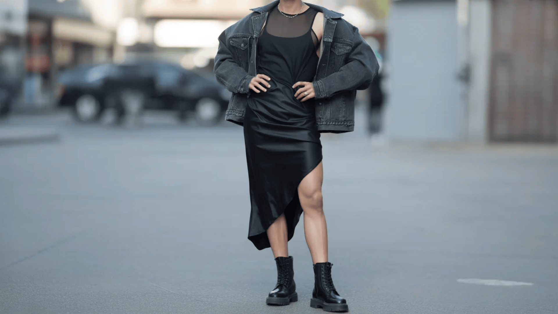 Indie sleaze look featuring a black slip dress layered with an oversized denim jacket and styled with chunky combat boots for a bold, feminine-meets-grunge street outfit