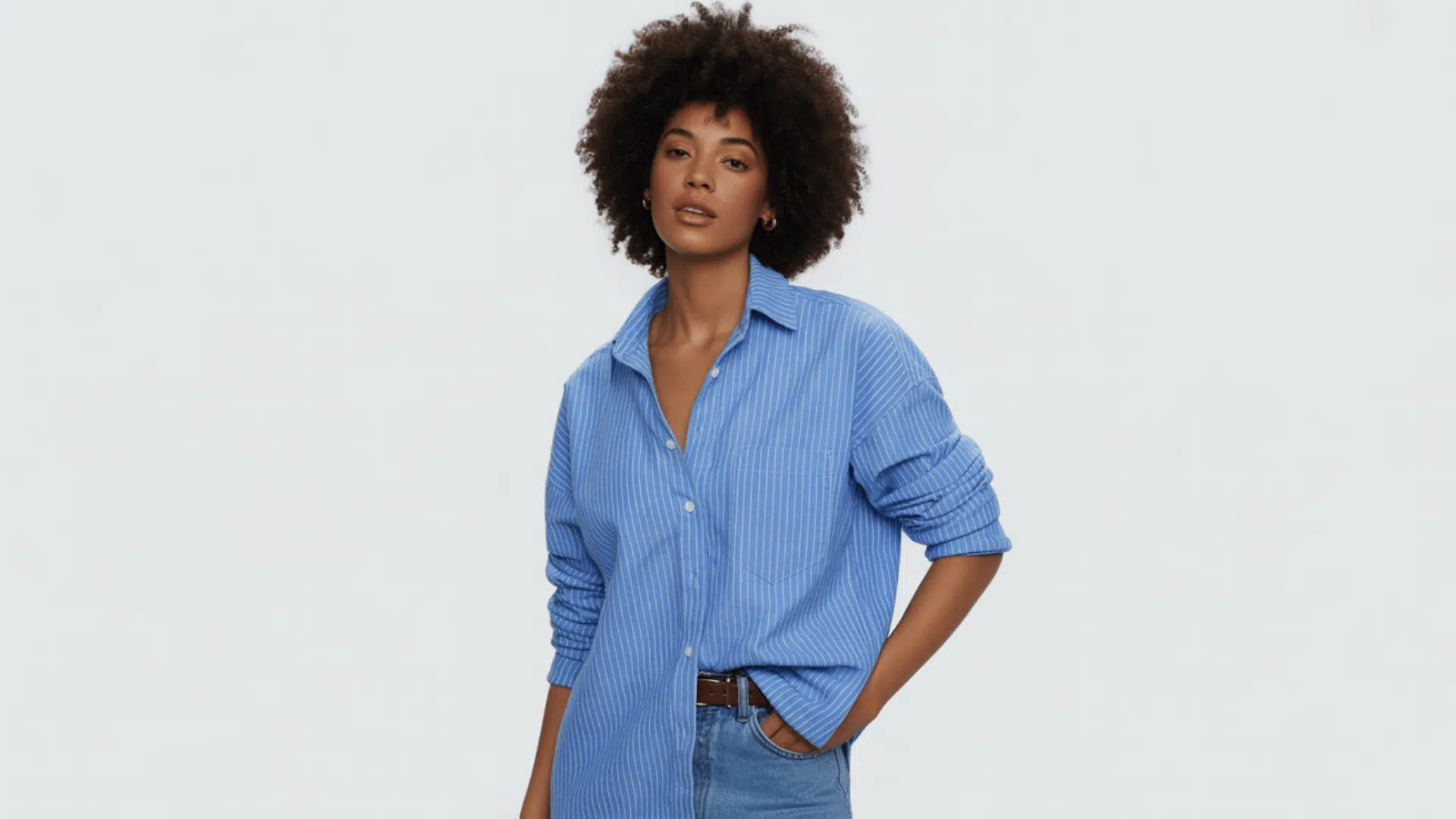 Woman wearing a classic blue button-down shirt with rolled sleeves styled in a relaxed fit.