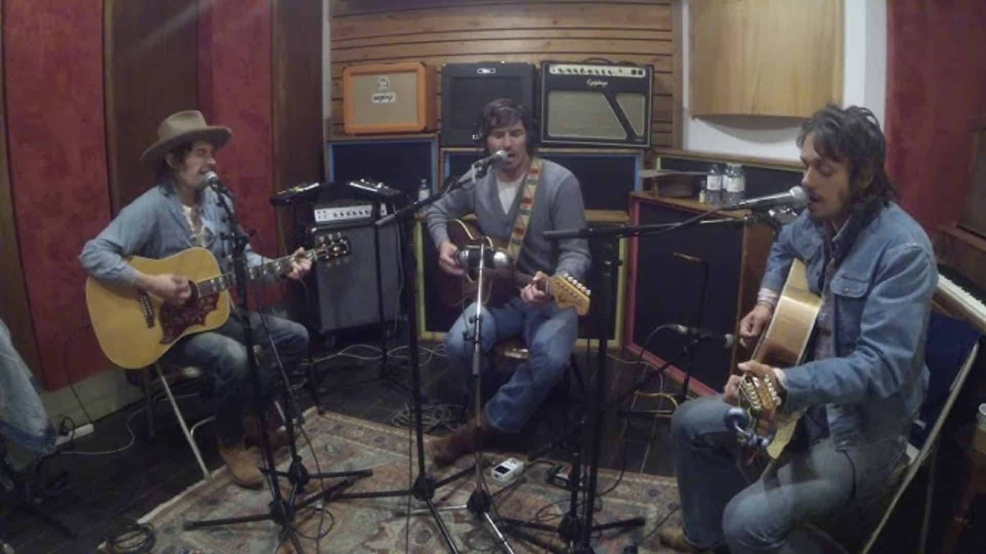 Midland band recording in a studio, playing guitars with amps and a wood-paneled background