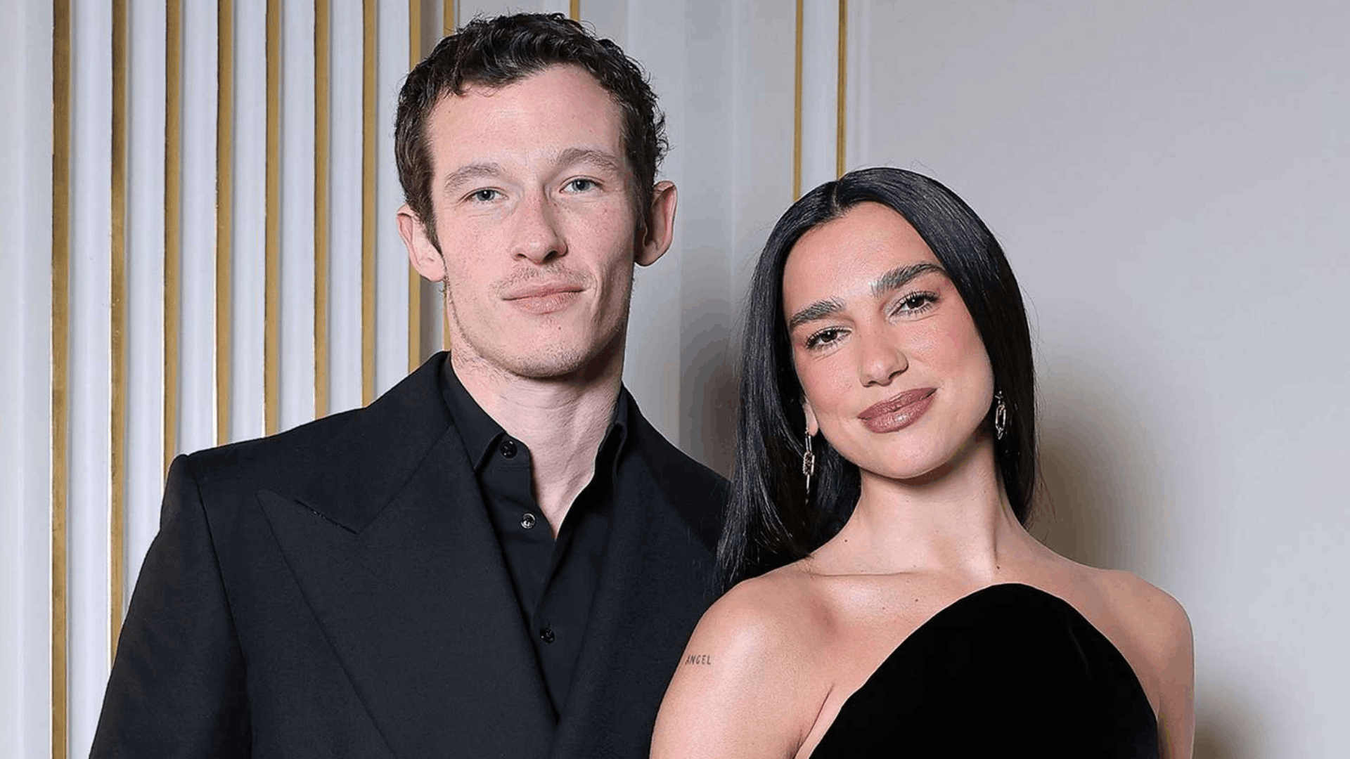Dua Lipa and Callum Turner smiling together at a public event.