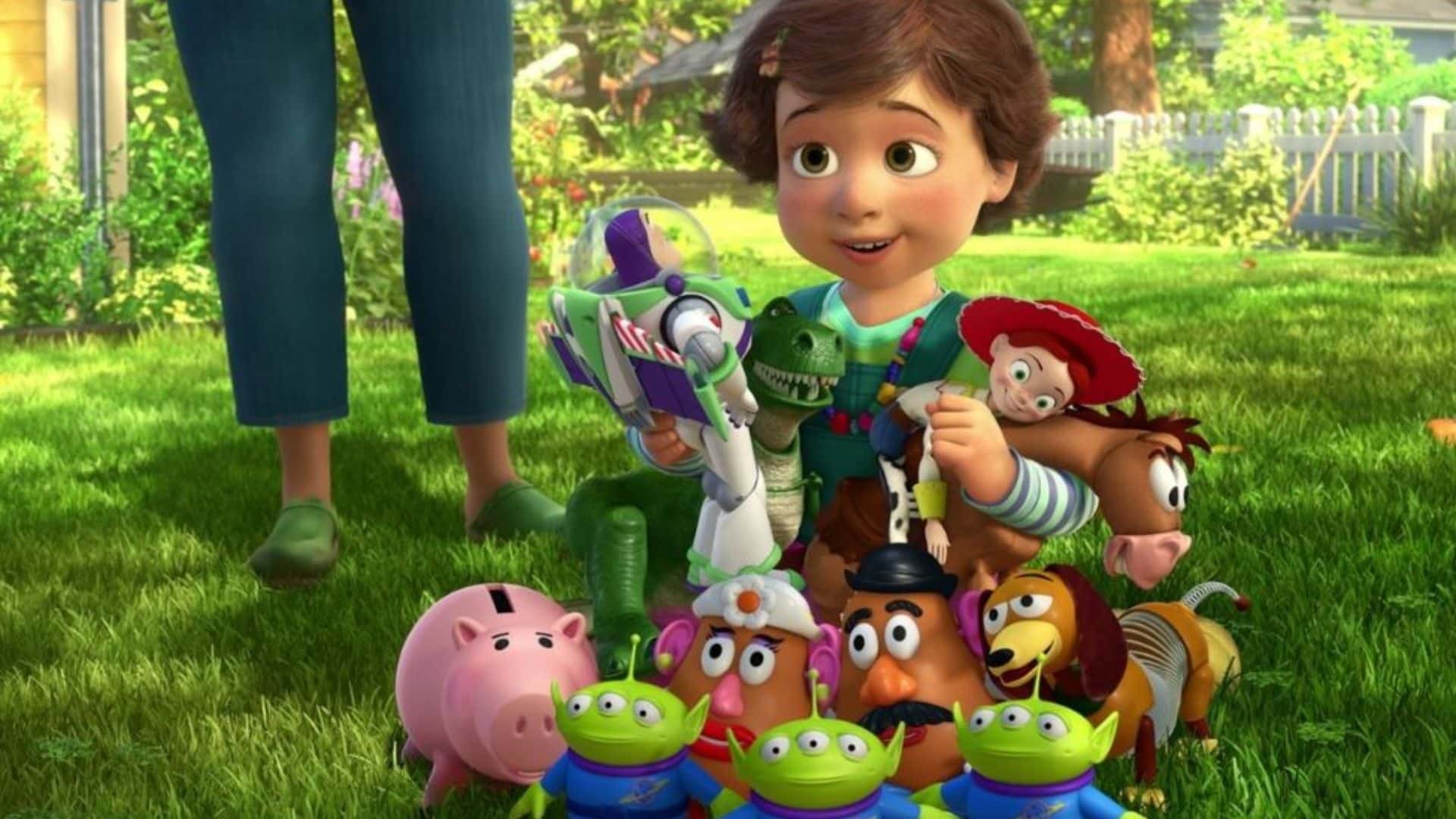 Bonnie Anderson playing with Woody, Buzz Lightyear, Jessie, Rex, Hamm, Slinky Dog, Bullseye, Mr. and Mrs. Potato Head, and the Little Green Aliens on a grassy lawn.