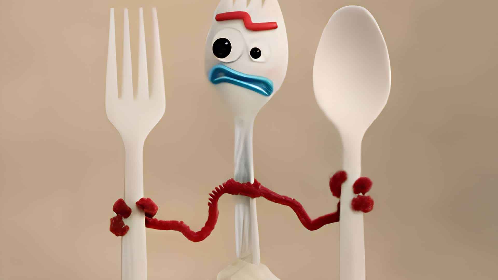 Forky from Toy Story 4 holding a plastic fork and spoon, with a surprised expression on his face.