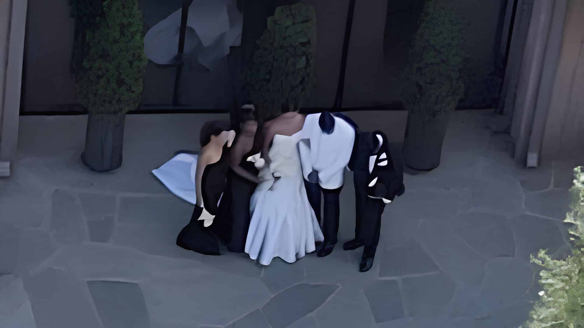 Bry Burrows and Jalen Hurts stand with guests during a private wedding celebration, with the bride in white and attendees dressed in black.