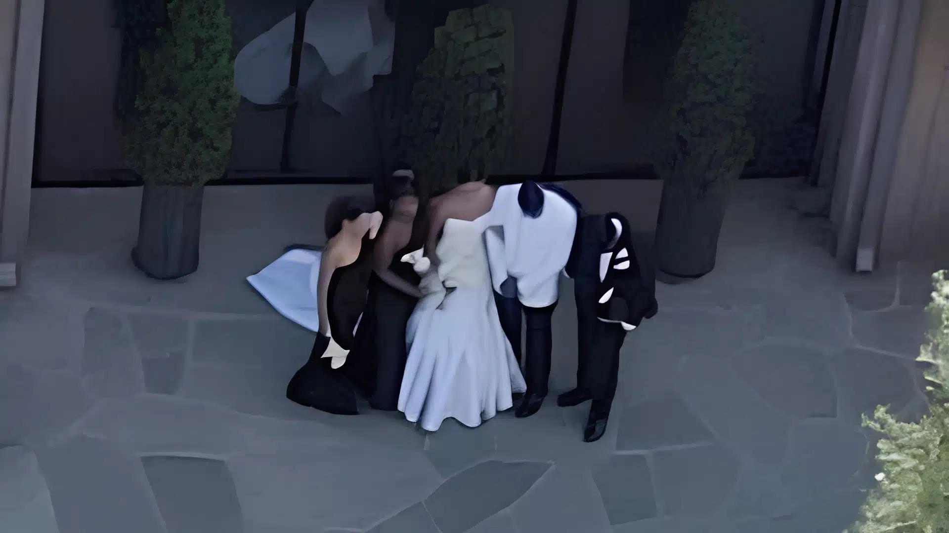 Bry Burrows and Jalen Hurts stand with guests during a private wedding celebration, with the bride in white and attendees dressed in black.