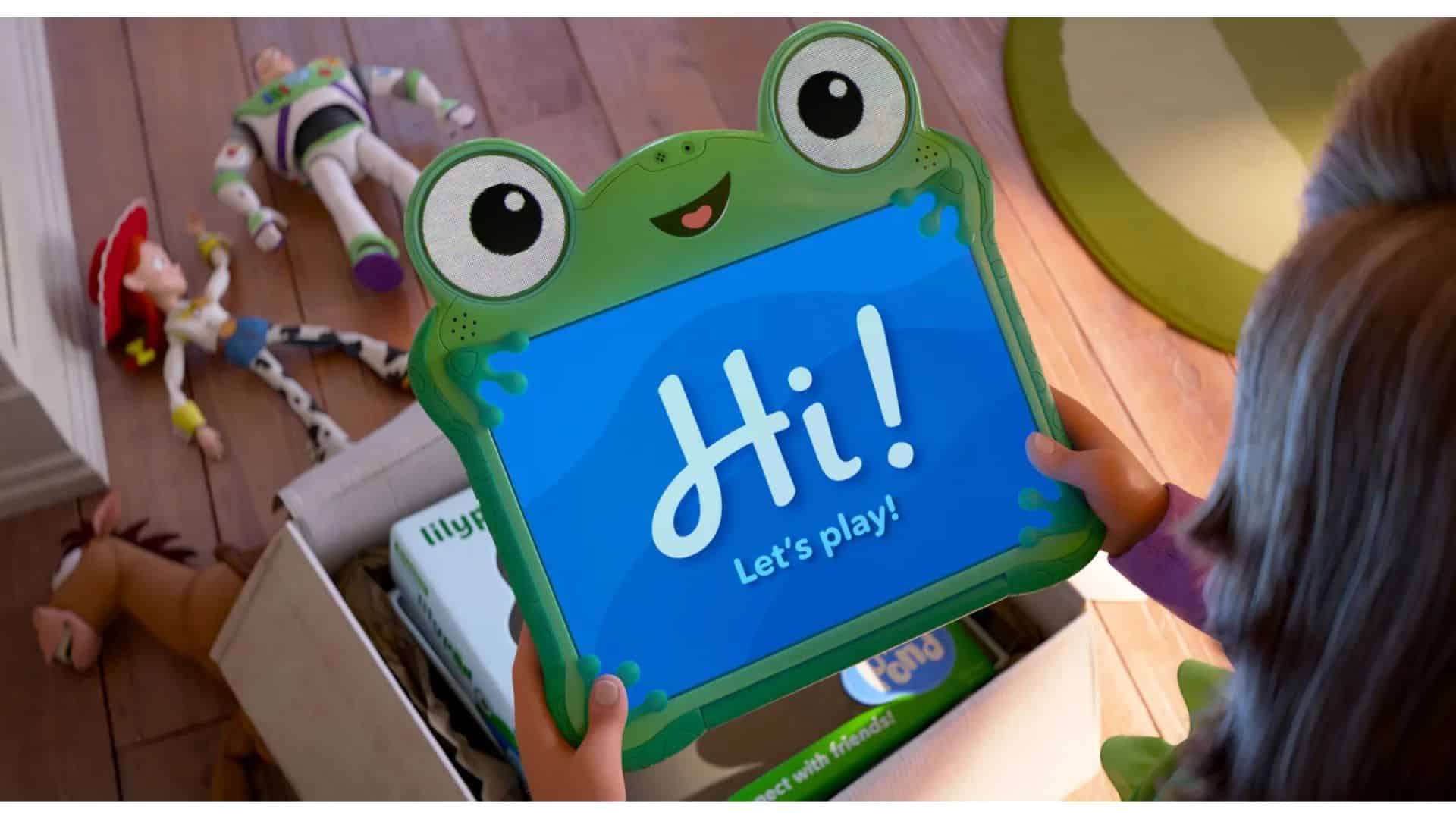 Lilypad, the frog-shaped smart tablet from Toy Story 5, held by Bonnie while Woody, Buzz, Jessie, and Bullseye appear in the background.