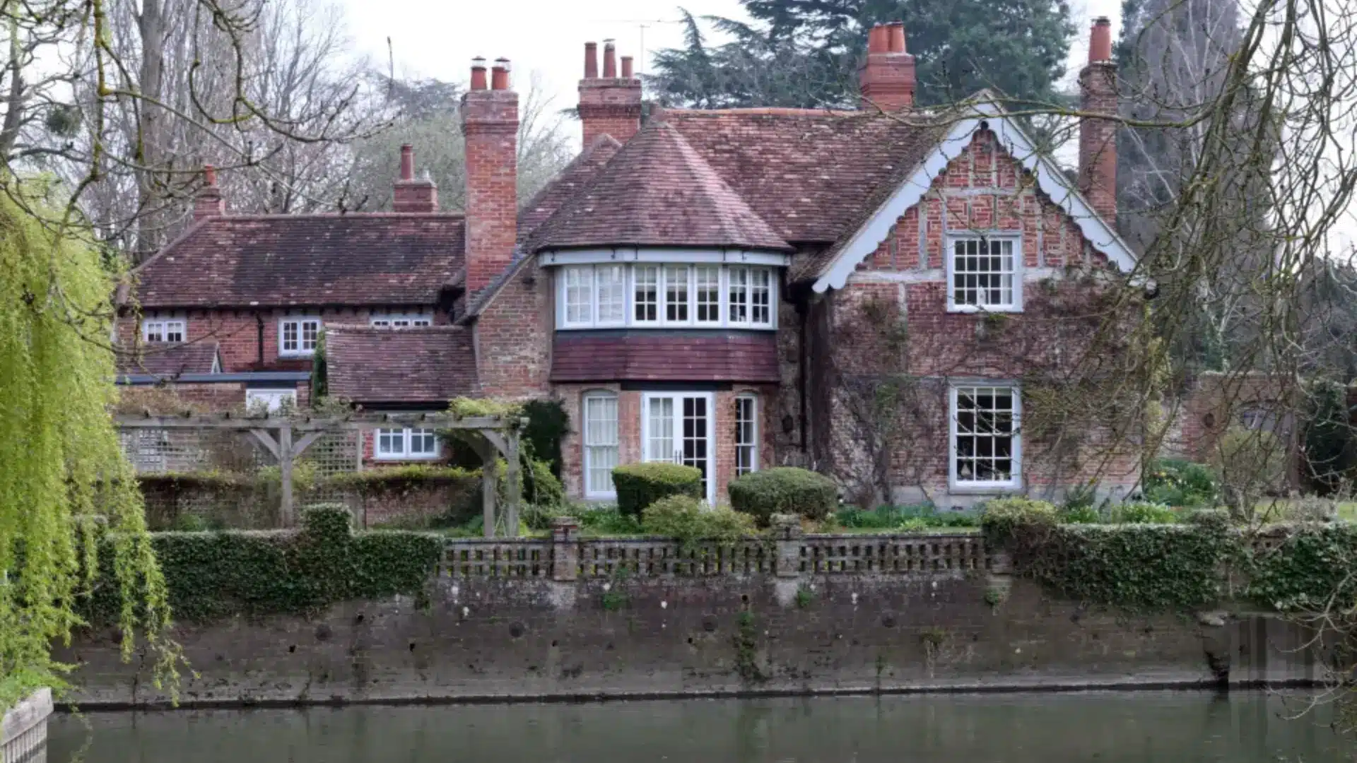 Large brick house with gardens and water in front representing George Michael’s real estate holdings.